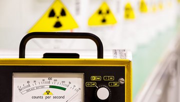 Das Foto zeigt ein Strahlungsmessgerät, im Hintergrund sind Behälter mit radioaktiven Stoffen zu erkennen