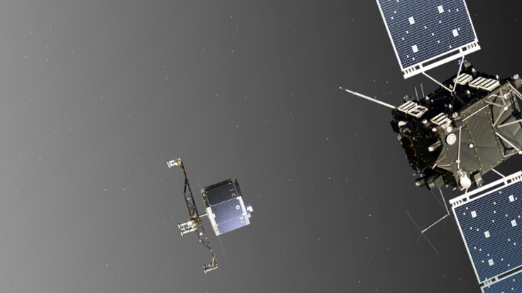 Rechts ein Raumfahrzeug mit großen Solarpanels, in der Mitte ein kleinerer Lander, links die Oberfläche des Kometen.