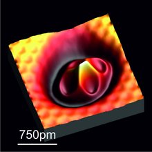 Aufnahme eines einzelnen Eisenatoms. Die unterschiedlich wirkenden Kräfte auf die Spitze des Kraftmikroskops sind in unterschiedlichen Farben dargestellt. In der Mitte erkennt man einen dunkelroten Kern, der nach außen heller wird. Umgeben von einem gelben Ring. Darauf folgt ein roter Ring. Die Größe des Eisenatoms umfasst ungefähr 250 Pikometer.
