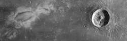 Schwarz-weiß Bild der Mondoberfläche, rechts ist ein kreisrunder Krater zu sehen, links ein weißer, unregelmäßiger Fleck, der noch länger ist als der Krater.