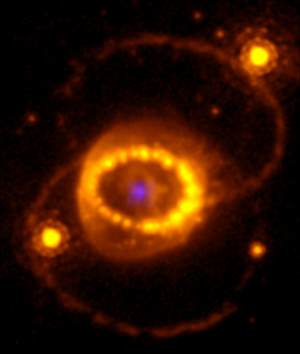 Ein violetter Punkt im Zentrum, der den Neutronenstern darstellt. Drum herum ein Ring aus Gas in orange. Links und rechts des orangenen Rings sind noch orangene Punkte. Das sind Sterne, die mit der Supernova nichts zu tun haben.