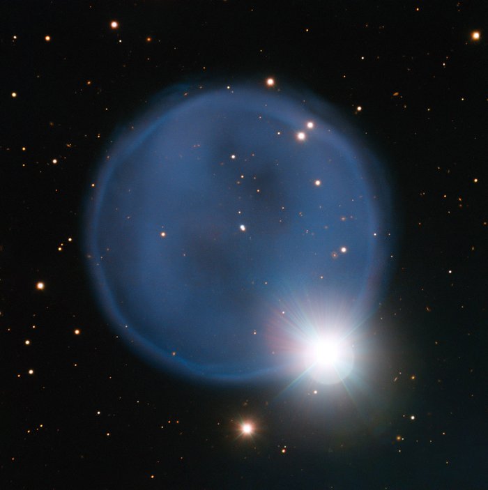 Eine kreisförmige Atmosphärenblase vor dem dunklem Sternenhintergrund des Weltalls. Am unteren rechten Rand der Blase leuchtet ein heller, kleiner Stern.