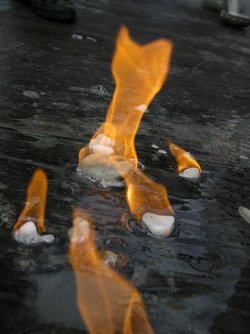 Kleine weiße Stückchen, wie Eis aussehend, liegen auf einem Tisch und brennen.