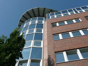 Bürogebäude mit Klinkerwand und spiegelnden Fenstern vor wolkenfreiem Himmel
