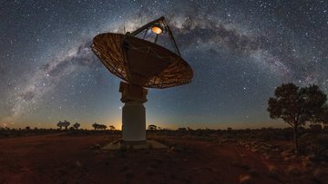 Im Vordergrund befindet sich ein Radioteleskop mit einer großen Schüssel. Im Hintergrund ist die Milchstraße abgebildet.