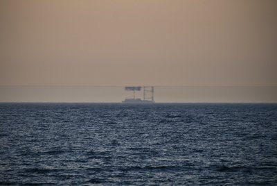 Das Foto zeigt ein Meer in der Abenddämmerung. Am Horizont ist ein Schiff zu erkennen, dass durch eine Luftspiegelung noch einmal auf dem Kopf stehend über dem eigentlichen Schiff zu sehen ist.