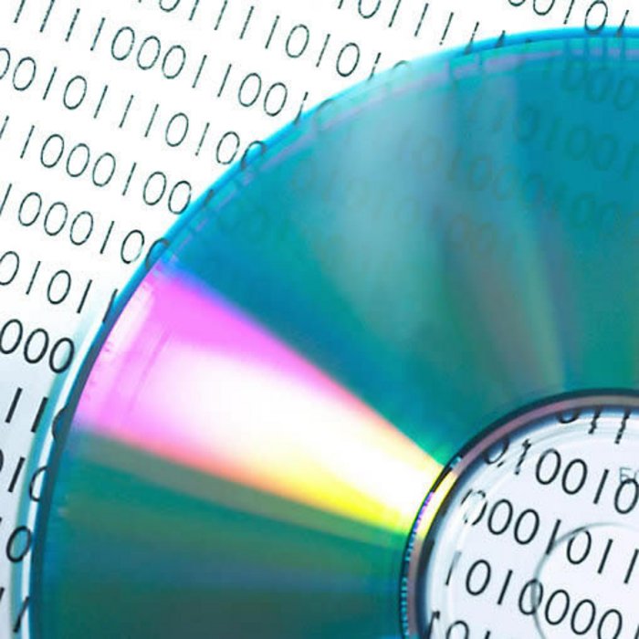 Nullen und Einsen auf Scheibe Eine CD liegt auf einem Blatt, das mit vielen Nullen und Einsen bedruckt ist.
