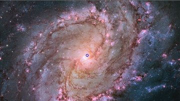 Spiralgalaxie, nahe dem Mittelpunkt befindet sich eine kleine kreisförmige Markierung.