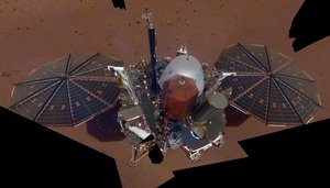 Ein Selfie vom Mars-Lander Insight auf dem Mars. InSight hat links und rechts zwei fast runde Solarpanele und steht auf dem rötlichen Marsboden.