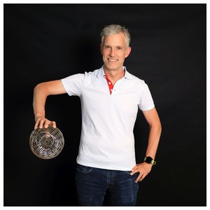 Porträt des Wissenschaftlers Markus Klute, der in der Hand eine runde Auszeichnung hält.