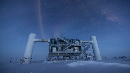 Ein Gebäude auf Stelzen, links und rechts mit jeweils einer weißen Säule verbunden, steht in einer nächtlichen Polarlandschaft