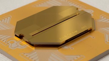 Nahaufnahme eines goldfarbenen Chips auf einer flexiblen Leiterplatte. Auf dem Chip sind feine, parallel verlaufende Leiterbahnen zu erkennen, die auf eine schmale, dunkle Rille in der Mitte zulaufen. 