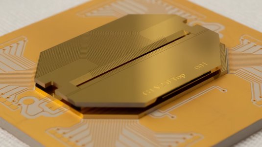 Nahaufnahme eines goldfarbenen Chips auf einer flexiblen Leiterplatte. Auf dem Chip sind feine, parallel verlaufende Leiterbahnen zu erkennen, die auf eine schmale, dunkle Rille in der Mitte zulaufen. 
