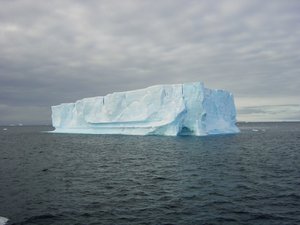 Ein großer Eisberg ragt aus dem Meer heraus.