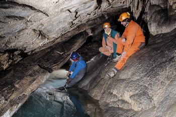 Auf dem Foto sind drei Forscher in einer Tropfsteinhöhle zu sehen.