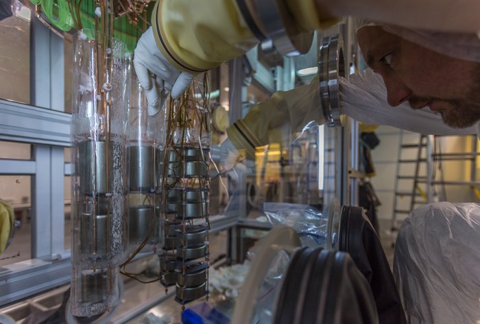 Arbeit am GERDA-Detektor Ein Wissenschaftler, mit großen Handschuhen ausgestattet, arbeitet innerhalb einer Box am Germaniumdetektor des GERDA-Experiments.