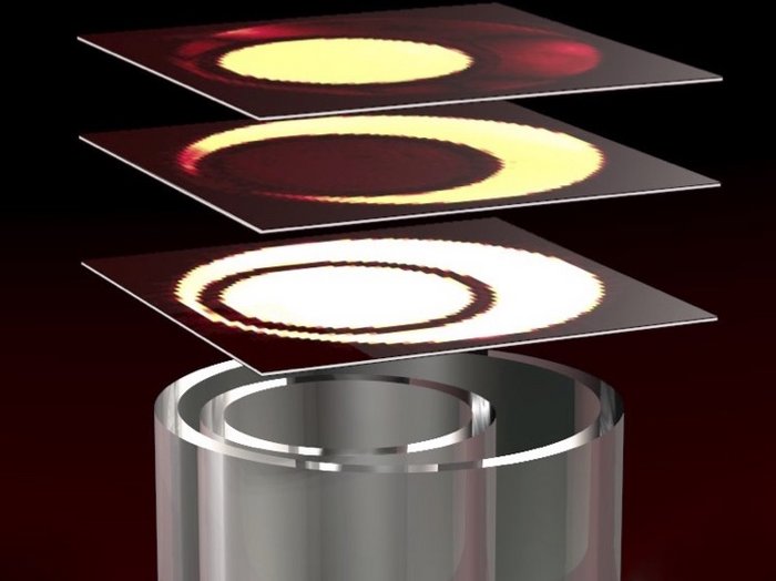 Magnetresonanztomografie Zylinderförmiges Objekt, über dem drei Platten schweben auf denen kreisförmige Muster abgebildet sind.