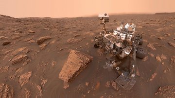 Der Mars-Rover Curiosity in einer steinigen Umgebung auf dem Roten Planeten
