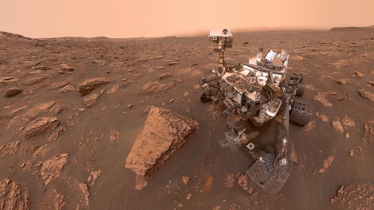 Der Mars-Rover Curiosity in einer steinigen Umgebung auf dem Roten Planeten