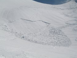 Foto: naher Blick auf einen schneebedeckten Berg, an dem eine rechtwinklige Schneekante zu sehen ist, dort wo sich eine Schnee-Lawine abgelöst hat. Dahinter wolkenloser Himmel.