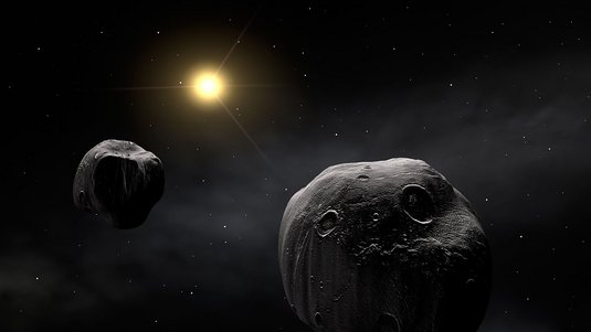 Zwei ungleich große Asteroiden vor fernem Stern und dunklem Hintergrund