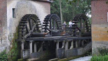 Das Bild zeigt einen Fluss mit Wasserrädern.