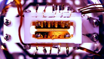 Eine goldene Ionenfalle, die das Herz des Quantencomputers darstellt, vor einem violettfarbenen Hintergrund.