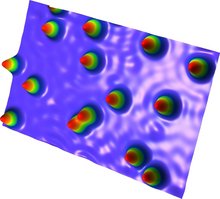 Metallische Platinoberfläche in 3D, aufgenommen mit einem Rastertunnelmikroskop. Einzelne Holmiumatome ragen als spitze Kegel aus der Oberfläche heraus.