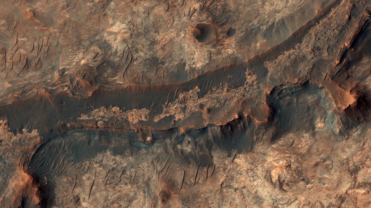 Luftaufnahme einer felsigen Landschaft auf dem Mars, auf dem eine geschwungene Vertiefung zu erkennen ist
