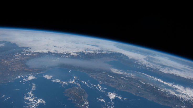 Ein Foto der Erdoberfläche aus großer Höhe. Es sind Wolken zu erkennen.