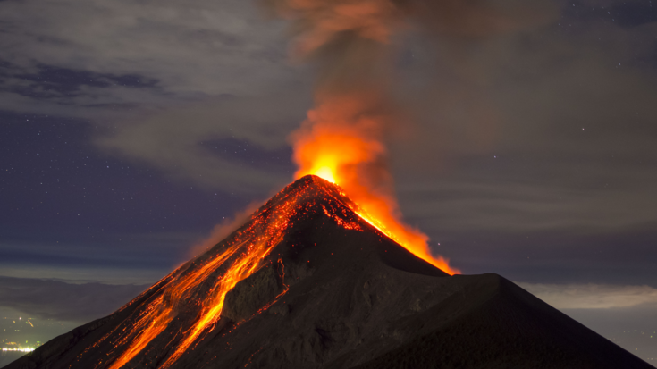 Foto eines Vulkanausbruchs, glühende Lava fließt am Vulkankegel hinunter 