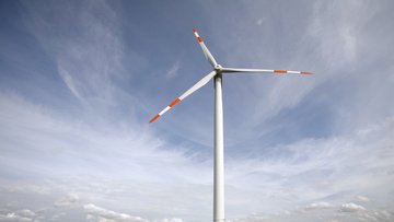 Das Bild zeigt die drei Rotorblätter eines Windkraftwerks vor dem Himmel.