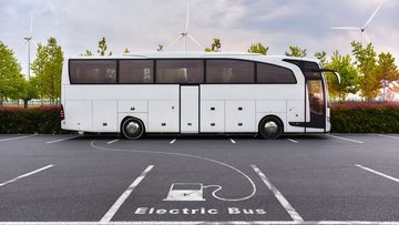 Ein Bus auf einem Parkplatz, ein Piktogramm mit einer Ladesäule auf dem Boden deutet an, dass es sich um einen Elektrobus handelt