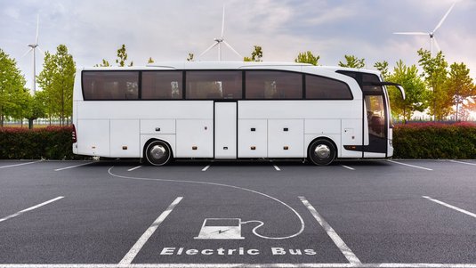 Ein Bus auf einem Parkplatz, ein Piktogramm mit einer Ladesäule auf dem Boden deutet an, dass es sich um einen Elektrobus handelt