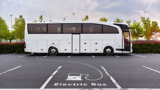 Ein Bus auf einem Parkplatz, ein Piktogramm mit einer Ladesäule auf dem Boden deutet an, dass es sich um einen Elektrobus handelt