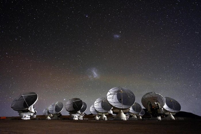 Radioteleskop ALMA Viele Parabolantennen, darüber der südliche Sternenhimmel mit den magellanschen Wolken
