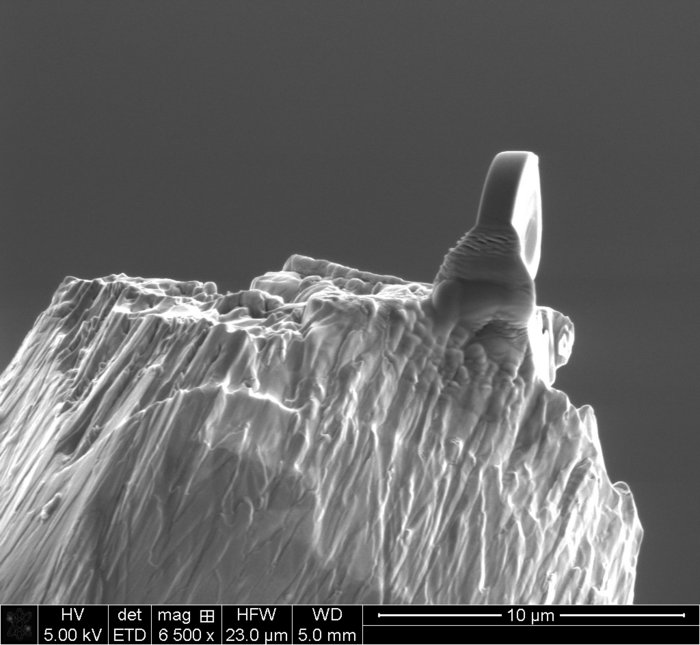 Eine winzige Röntgenlinse sitzt auf einer Nadelspitze. Unter dem Elektronenmikroskop wirkt sie wie ein Fels auf einem schroffen Bergkamm.