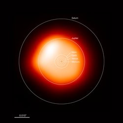 Die Aufnahme zeigt Beteigeuze als einen leuchtenden Kreis. Die Helligkeit nimmt nach außen ab. Zum Vergleich sind die Orbits der Planeten unseres Sonnensystems als Kreise um das Zentrum von Beteigeuze eingezeichnet. Während die Orbits von Merkur, Venus, der Erde, Mars und Jupiter noch im Stern liegen, reicht lediglich der Orbit von Saturn bis über die Grenzen von Beteigeuze hinaus.