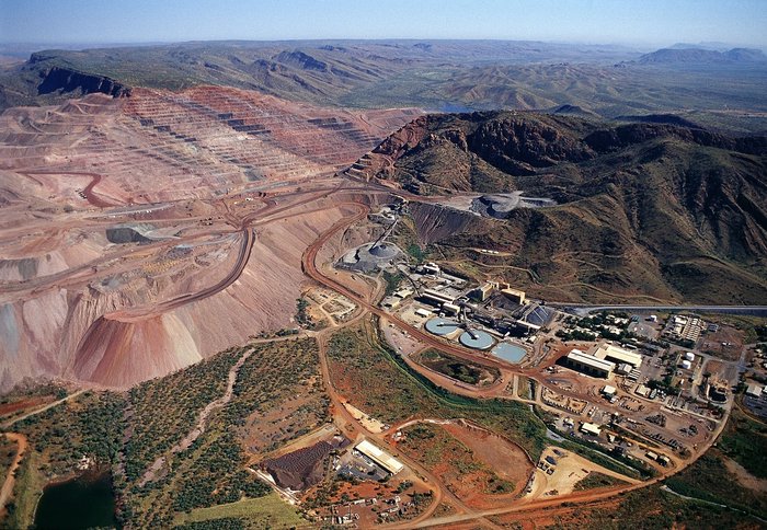Argyle-Diamantenmine Luftaufnahme eines Bergwerks: links zeigen sich terrasenförmige Formationen in einer unbewachsenen Gegend, rechts mehrere technische Anlagen und Gebäude