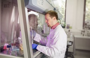 Der Wissenschaftler Sander Bekeschus führt ein Experiment in einem Labor durch. Dazu steht er an einem großen Gerät im gläsernen Innenraum und füllt etwas aus einer Pipette in ein anderes Gefä?.