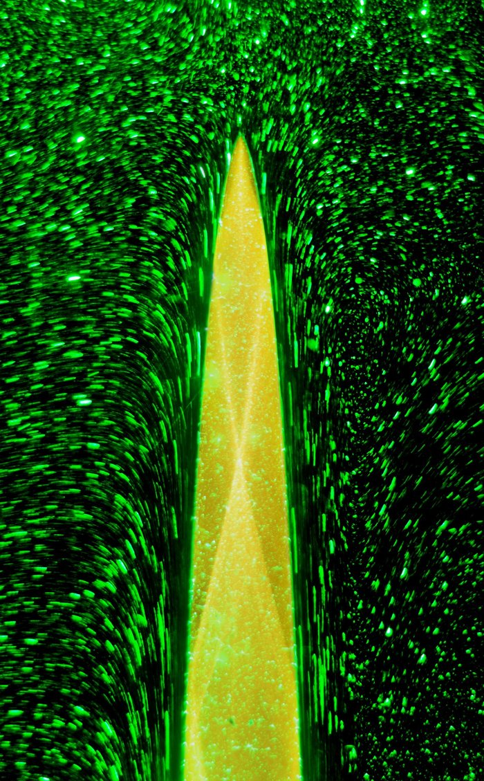 Bonbonzylinder unter Wasser Computergrafik: Ein grüner, spitz aufragender Körper umgeben von grünen Punkten auf schwarzem Hintergrund