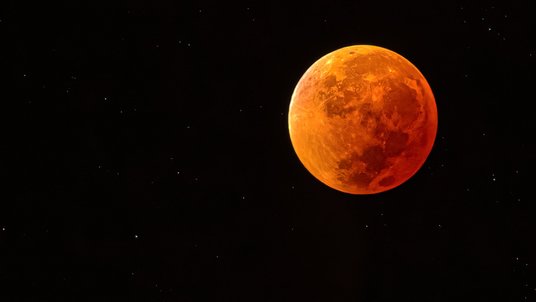 rötlich gefärbter Vollmond am Nachthimmel