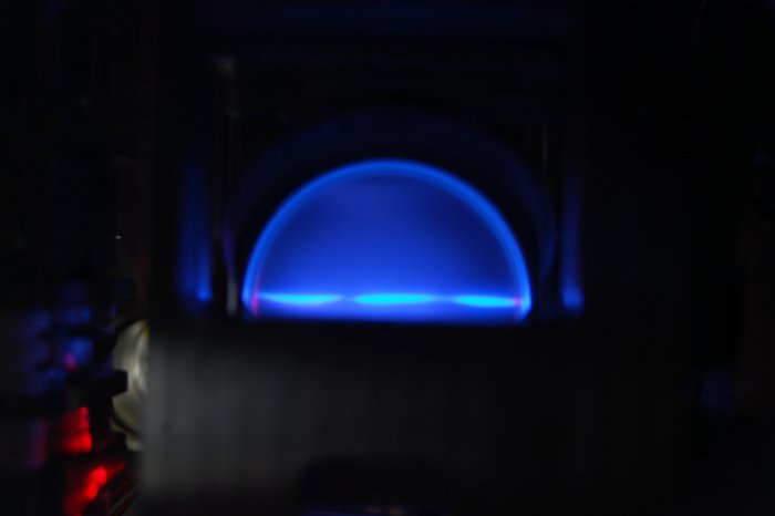 Eine Halbkugel aus blauem Licht leuchtet leuchtet über einer Fläche in einem ansonsten dunklen Raum.