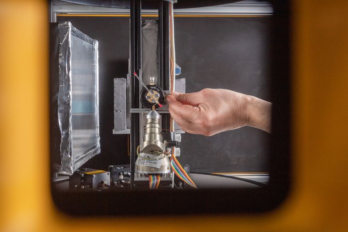 Das Instrument BioDiff Blick durch eine fensterähnliche Öffnung: Eine Hand richtet etwas an einer länglichen Apparatur