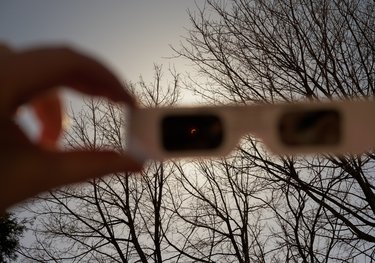 Das Foto zeigt den Blick durch eine Finsternisbrille auf eine Sonnenfinsternis.