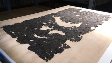Verkohlte Papyrusschnipsel liegen auf einem Tisch