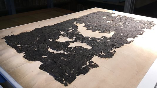 Verkohlte Papyrusschnipsel liegen auf einem Tisch