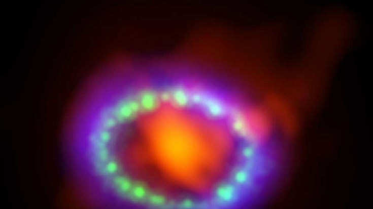 Supernova 1987A, Bildquelle: Alexandra Angelich (NRAO/AUI/NSF), NASA; Lizenz: gemeinfrei Bunte, ovale Struktur auf dunklem Hintergrund.