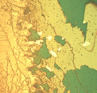 Ein zackiges Muster aus grünen und gelben Zonen zeigt verschiedene Strukuren eines Kolloidkristalls. 