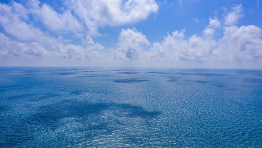 Die Aufnahme zeigt den Horizont, in der unteren Hälfte befindet sich Wasser, darüber Luft mit Wolken.